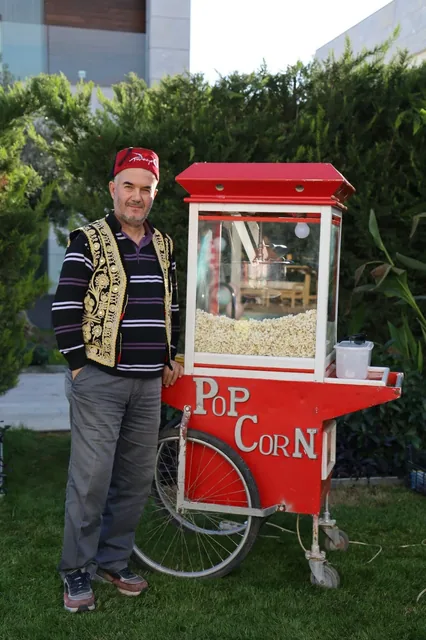 Geleneksel kıyafetli görevli ve kırmızı popcorn arabası