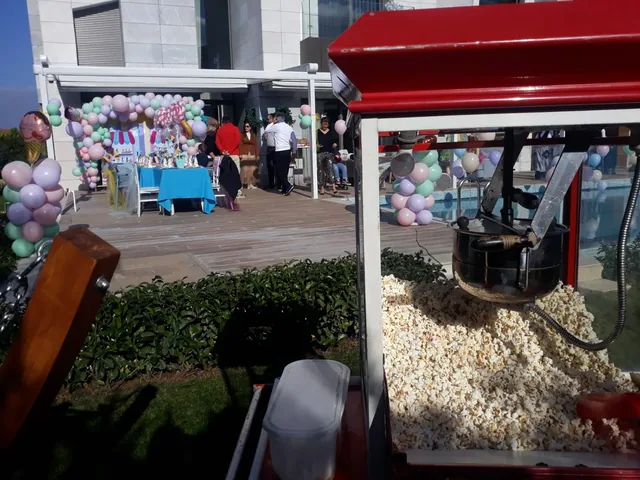 Bahçe kutlamasında kırmızı popcorn makinesi ve balon süslemeleri