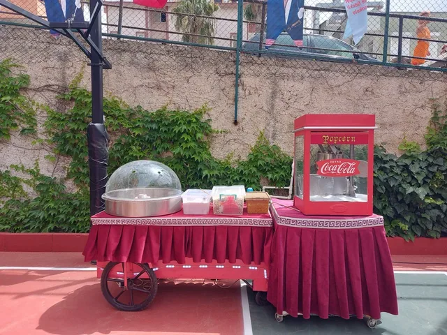Okul bahçesinde kırmızı araba üzerinde pamuk şeker ve popcorn makineleri